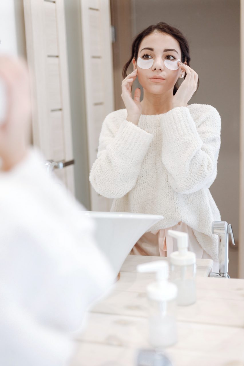 Woman using Skincare products in front of a mirror